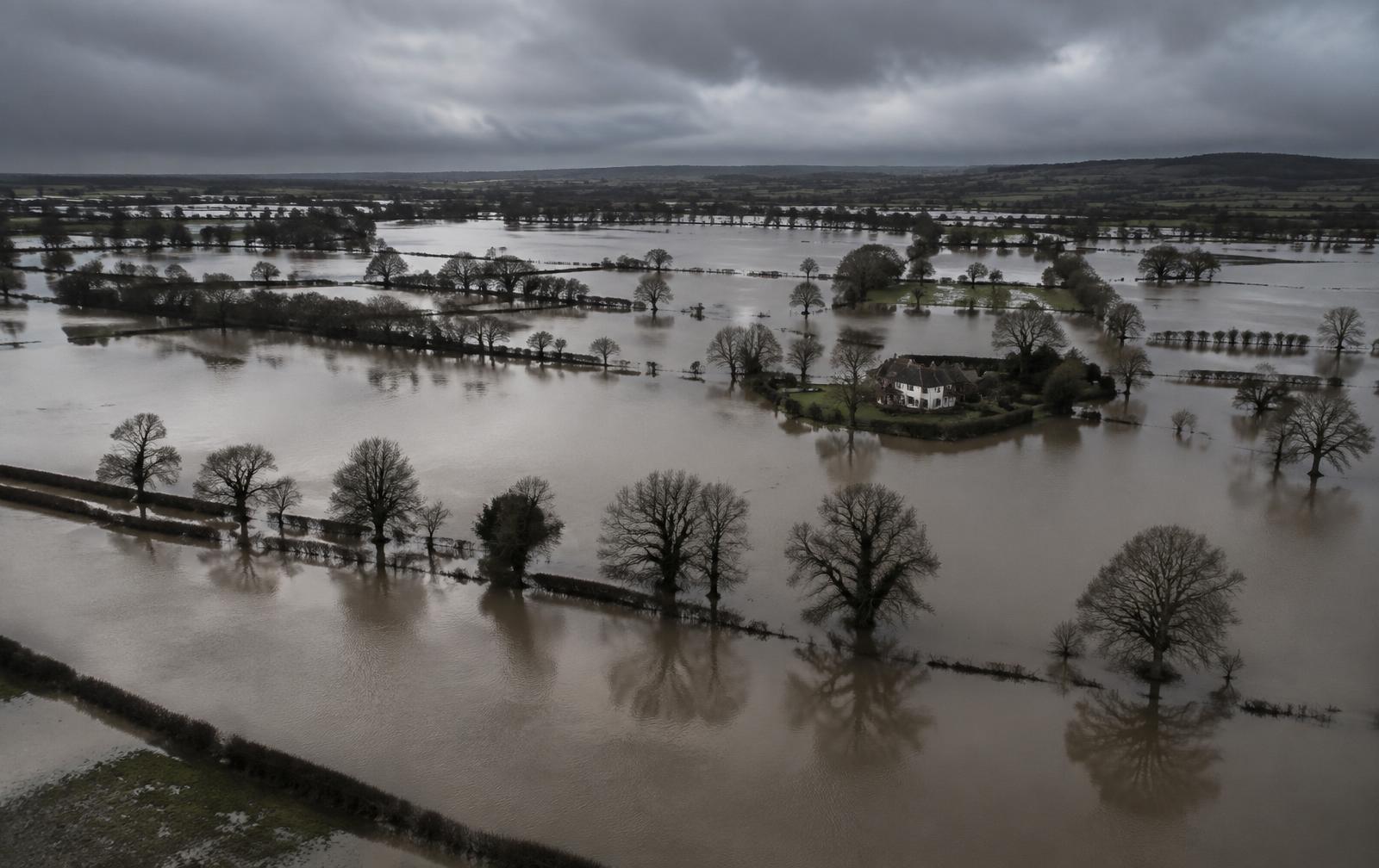Flooded UK farmland under a heavy overcast sky
